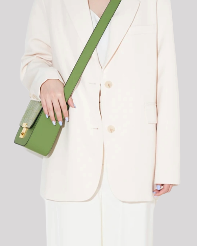 Green croc-embossed shoulder bag by Bafelli worn crossbody with thick strap, styled with cream outfit