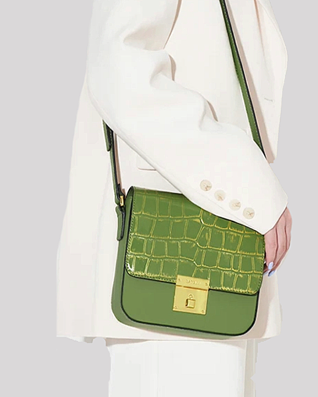 Green croc-embossed shoulder bag by Bafelli worn crossbody with adjustable strap, shown on model in white blazer