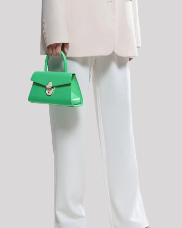Model holding green mini top-handle bag by Bafelli with pearl clasp and structured silhouette