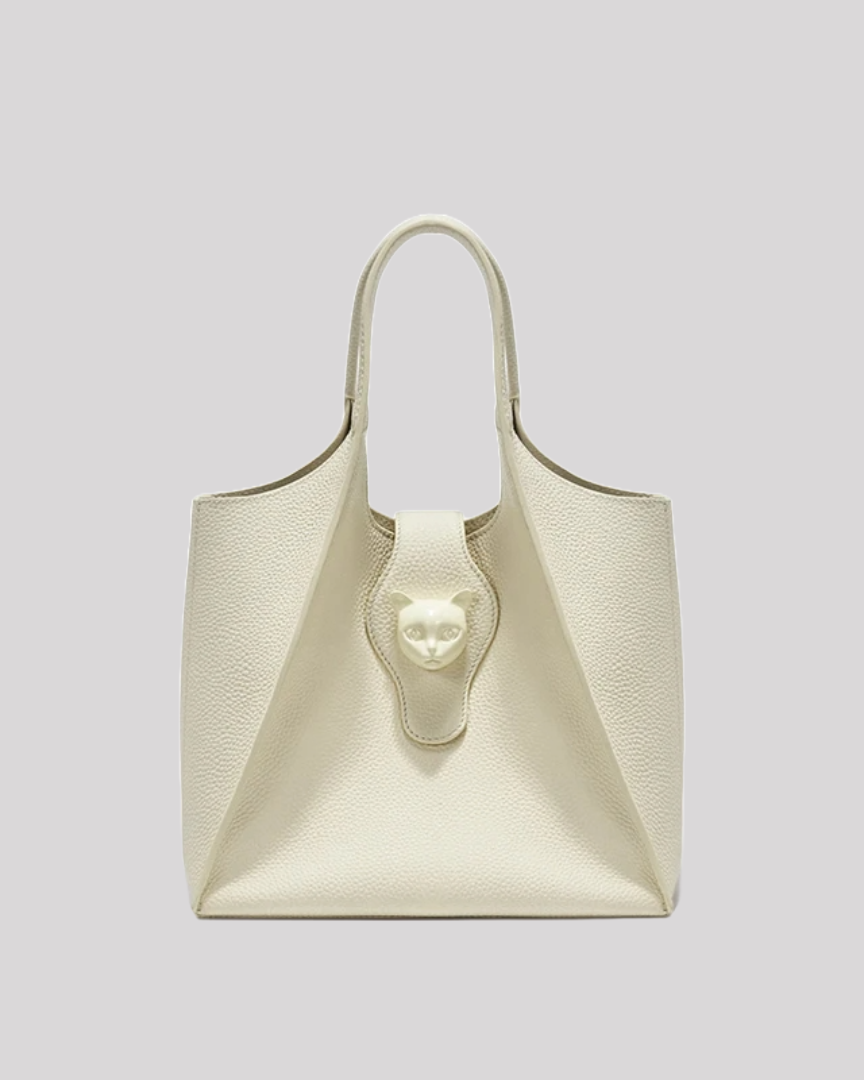 Front view of ivory leather tote bag by Bafelli with embossed cat emblem clasp and structured silhouette