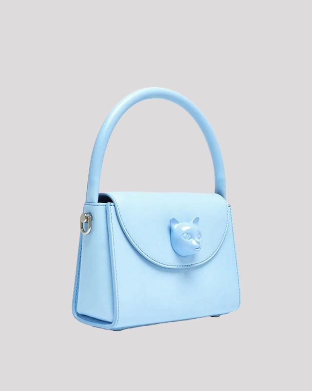 Side angle view of light blue handbag by Bafelli with structured design and cat face detail
