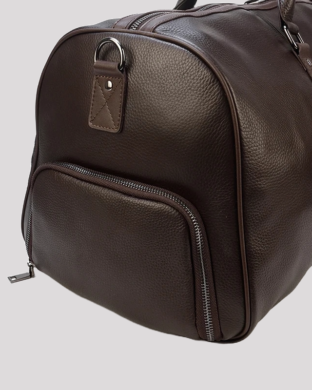 Close-up of side shoe compartment on men’s brown leather duffle bag
