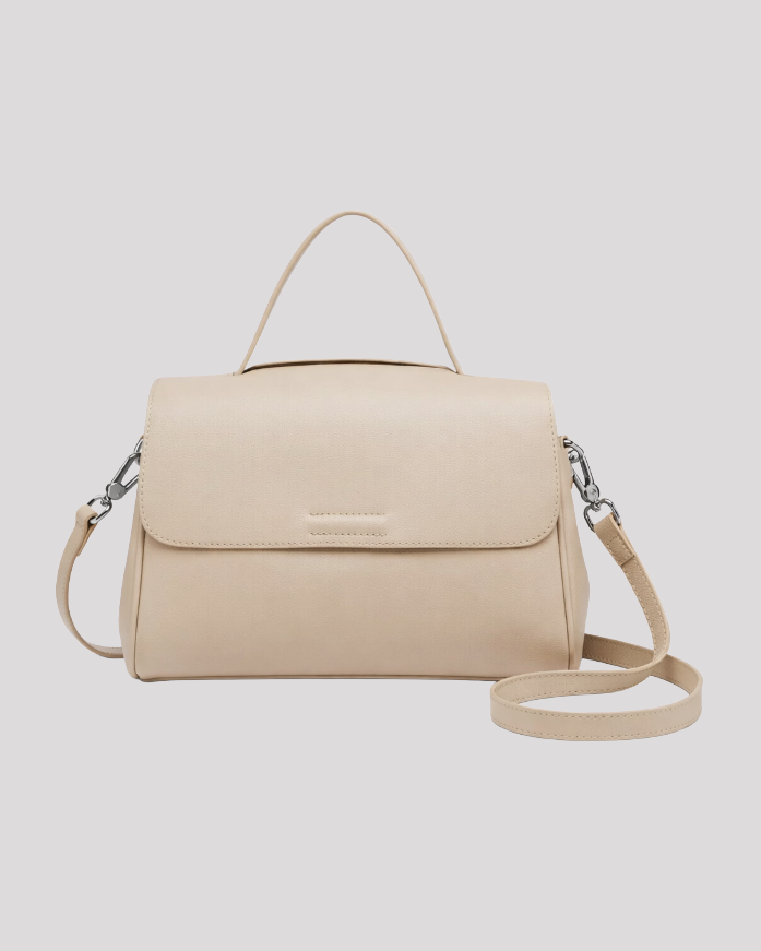 Front view of minimal beige leather top handle bag with flap closure and detachable shoulder strap