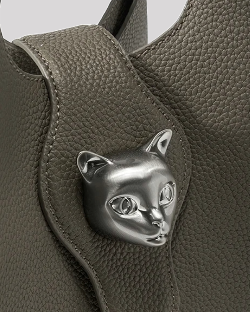 Close-up of silver cat emblem clasp on textured olive green leather tote bag by Bafelli