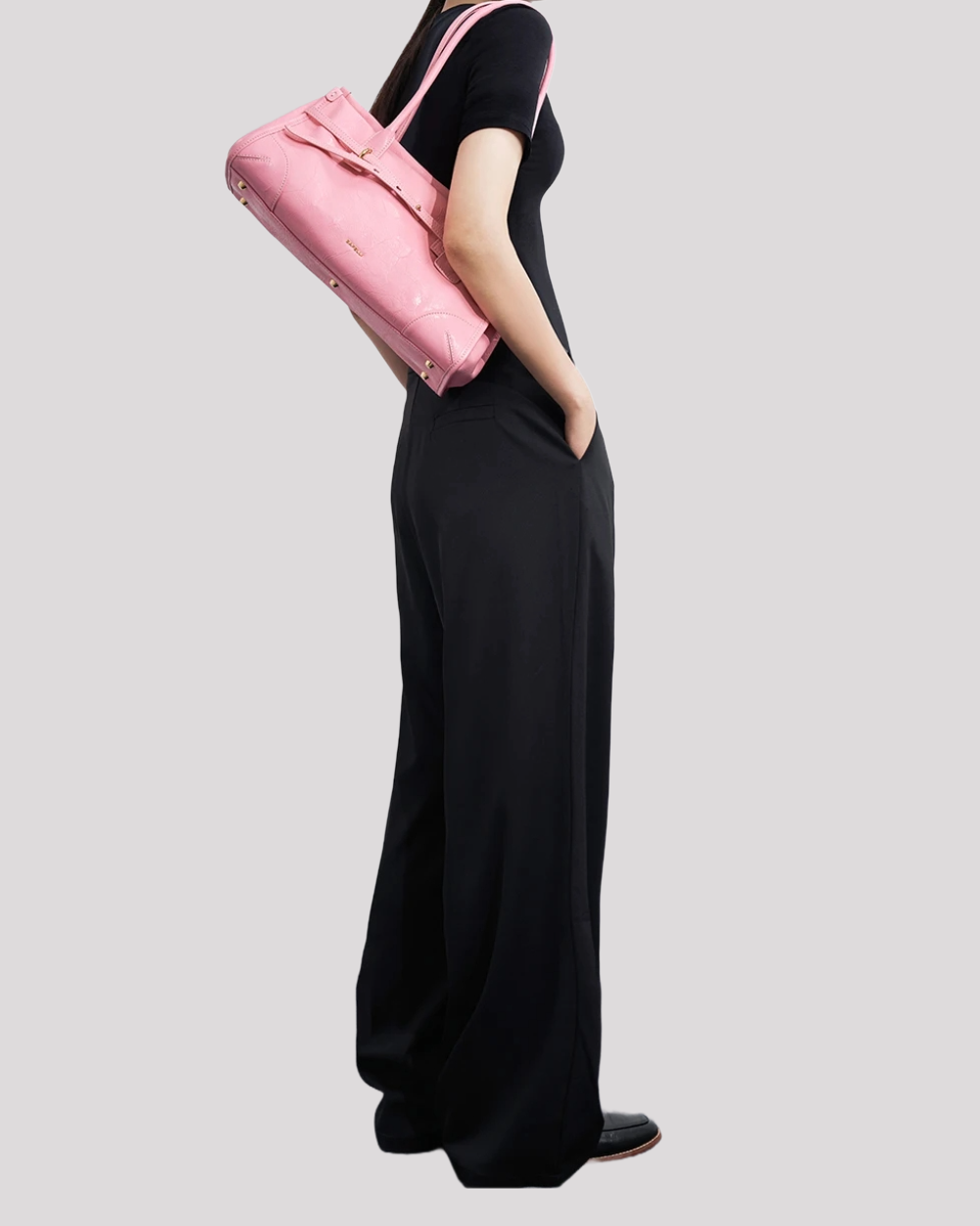 Full body view of woman wearing black outfit with pink leather shoulder bag by Bafelli
