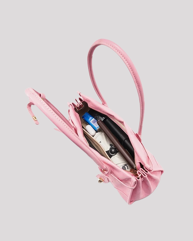 Open top view of pink leather shoulder bag by Bafelli filled with daily essentials