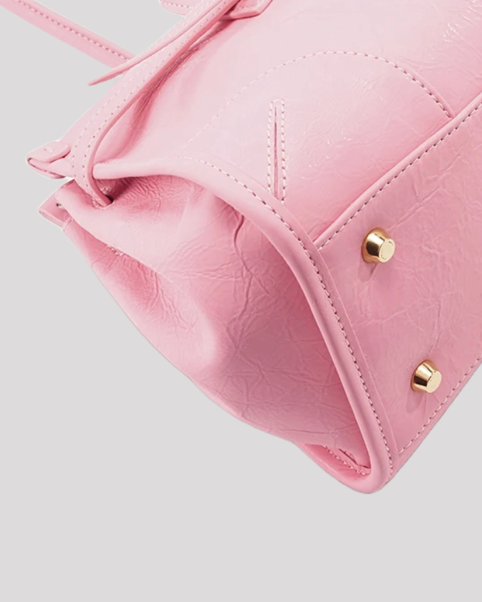 Close-up of bottom corner stitching and gold studs on pink leather shoulder bag by Bafelli