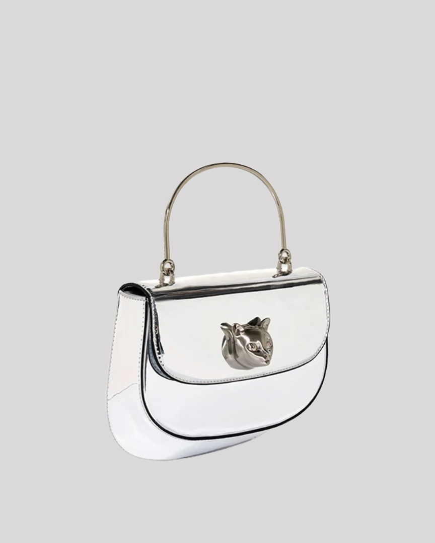 Side angle of silver metallic handbag by Bafelli with structured design and cat emblem clasp