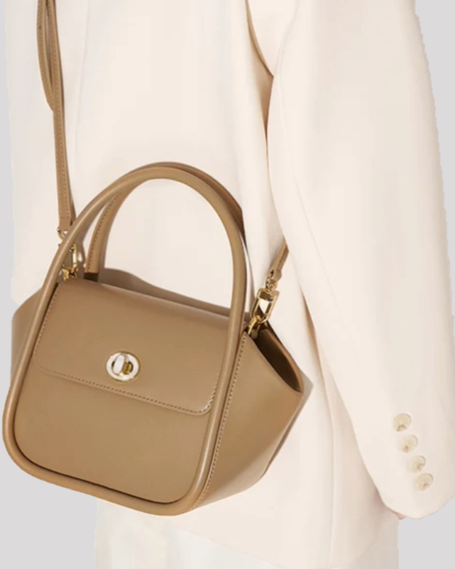 Taupe structured leather handbag by Bafelli worn over the shoulder with detachable strap, paired with cream blazer