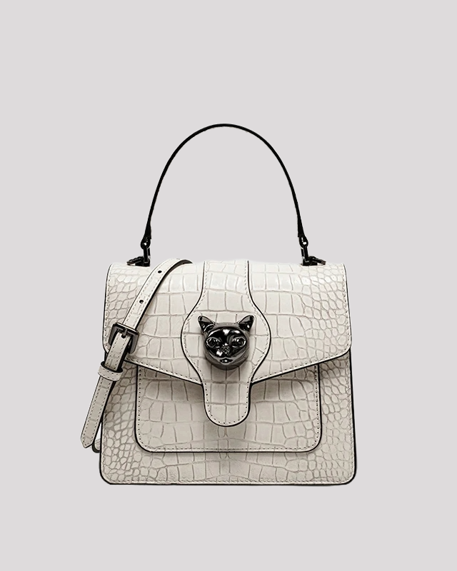 Front view of white croc-embossed leather handbag by Bafelli with black cat head clasp and top handle