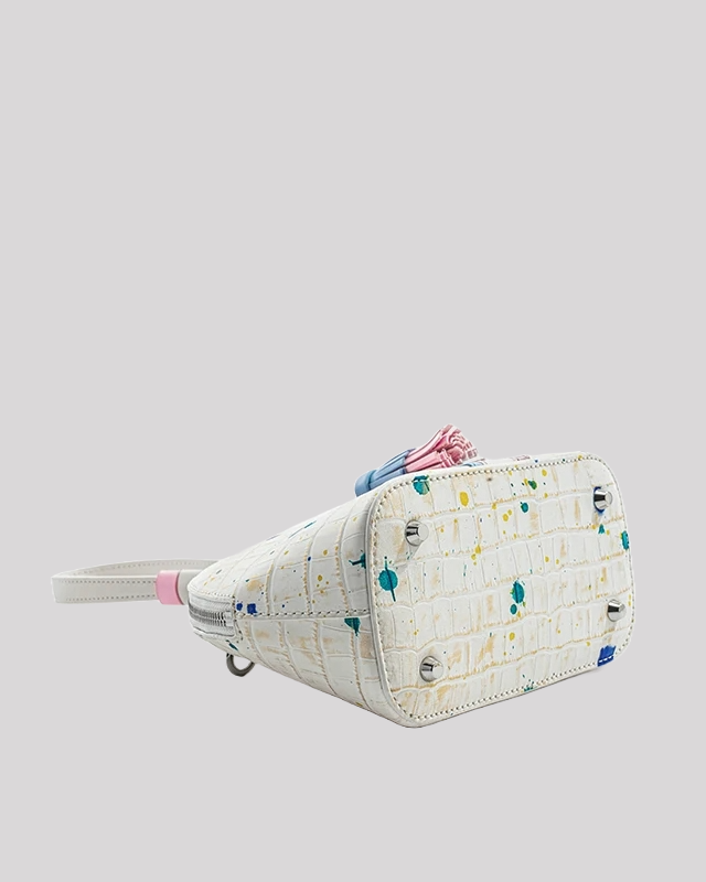 Bottom view of white crocodile-embossed wristlet bag by Bafelli with protective metal feet and colorful paint-splatter finish