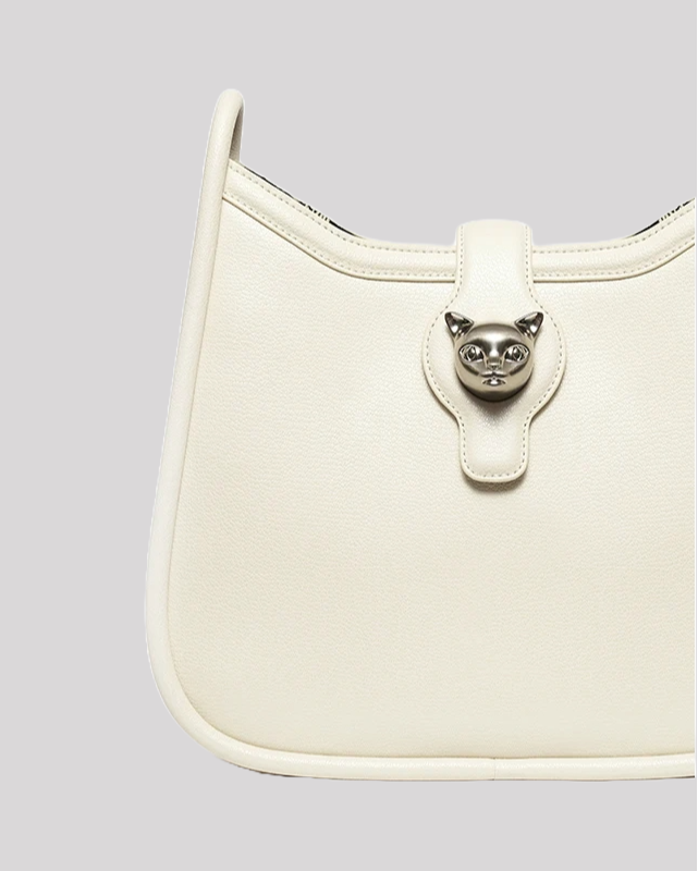 Close-up of white leather shoulder bag front with silver cat head clasp detail