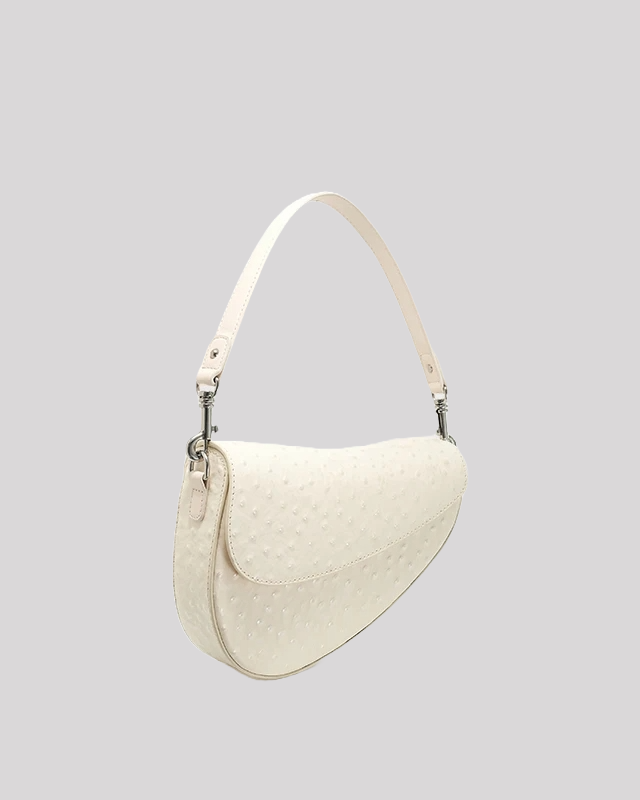 Side angle of white ostrich-embossed asymmetric shoulder bag by Bafelli showing curved silhouette