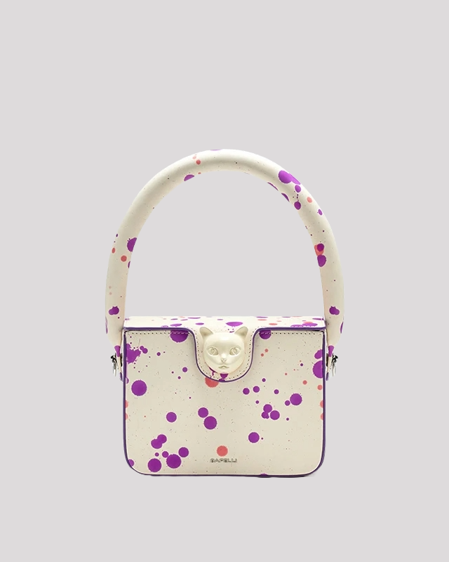 White mini handbag by Bafelli with purple and pink splatter design and cat clasp – front view