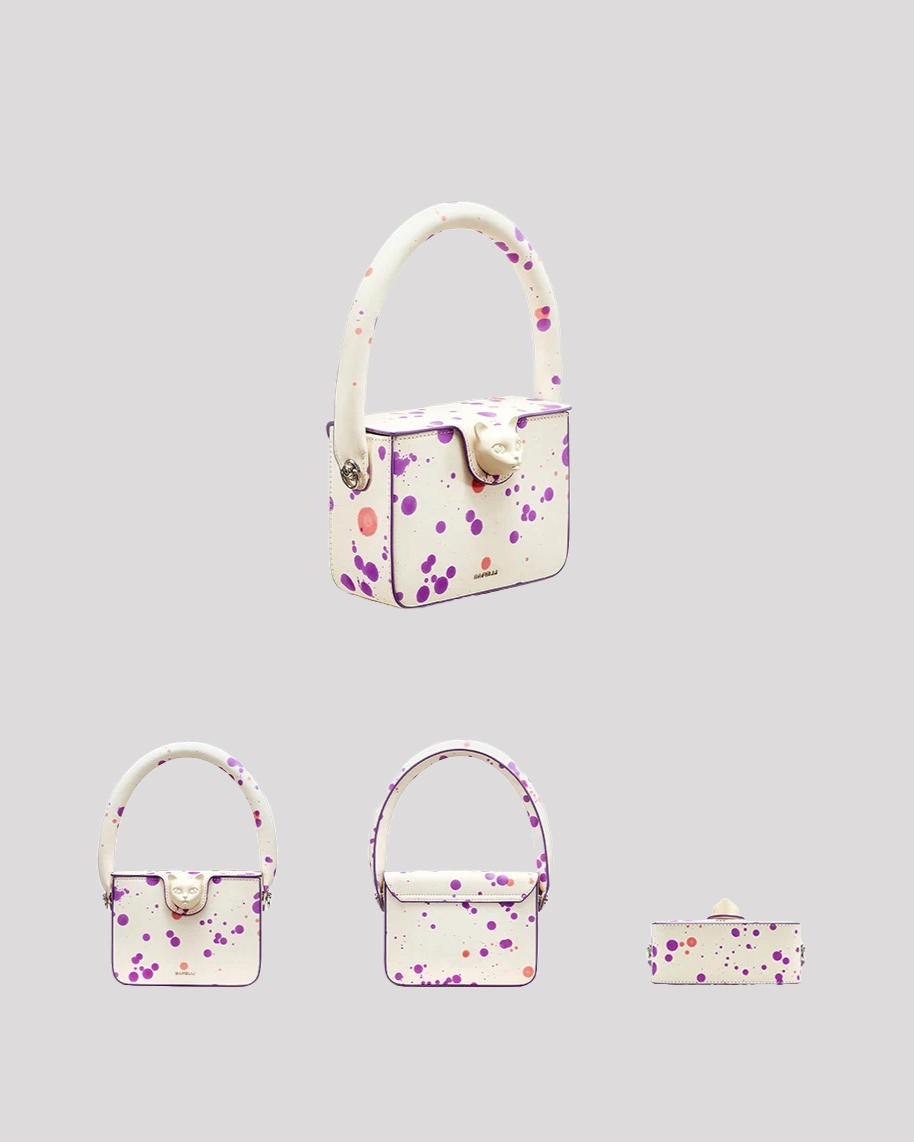 Multi-angle view of white mini handbag by Bafelli with purple splatter design and top handle