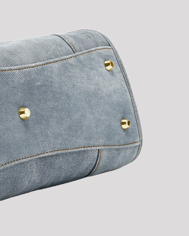 Close-up of the bottom of women’s blue leather tote bag by Bafelli with gold studs