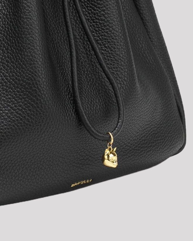 Women’s black leather bucket bag by Bafelli – close-up detail of gold-tone charm and textured leather