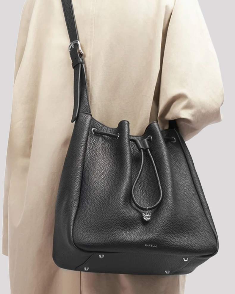 Women’s grey leather bucket bag by Bafelli worn over the shoulder – elegant handbag styled with adjustable strap