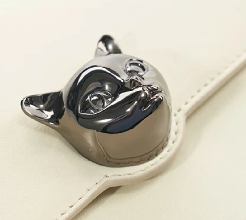 Close-up of women’s crossbody bag by Bafelli in white leather – metallic cat head clasp detail
