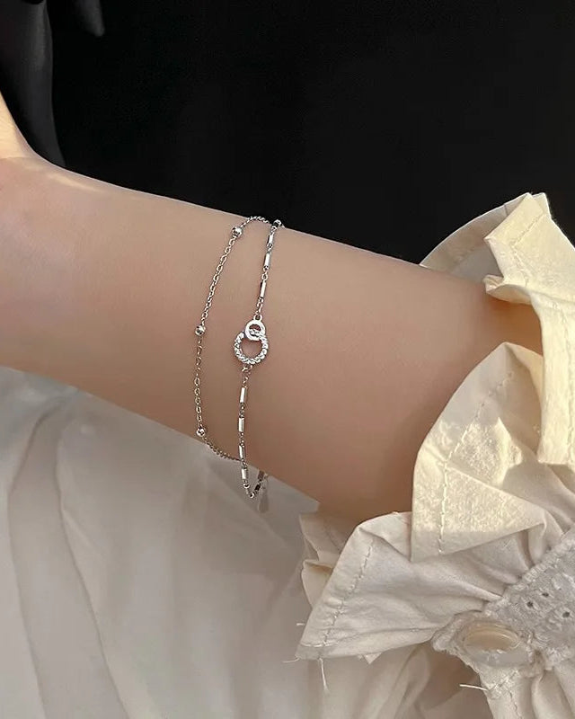 Elegant women’s silver bracelet with heart and circle charm – styled on wrist with outfit