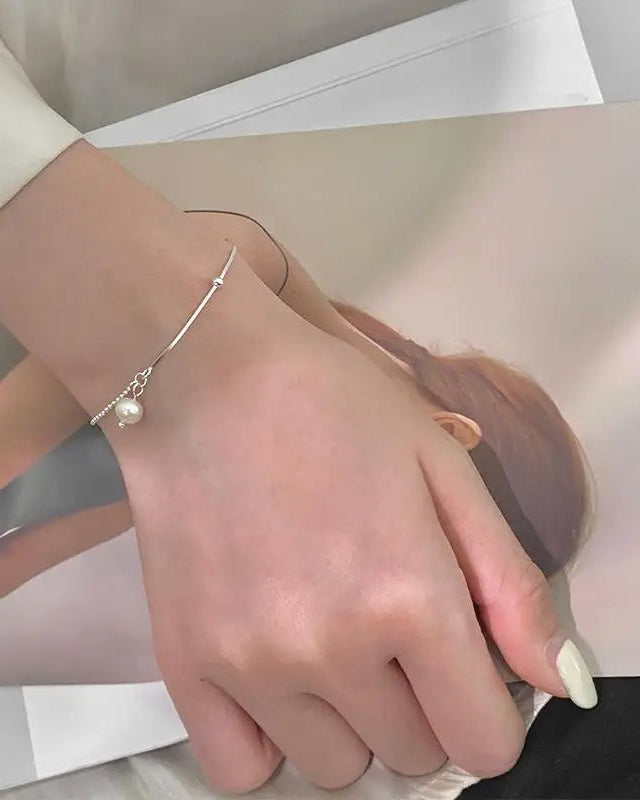 Women’s silver bracelet with delicate chain and pearl pendant – elegant wrist close-up