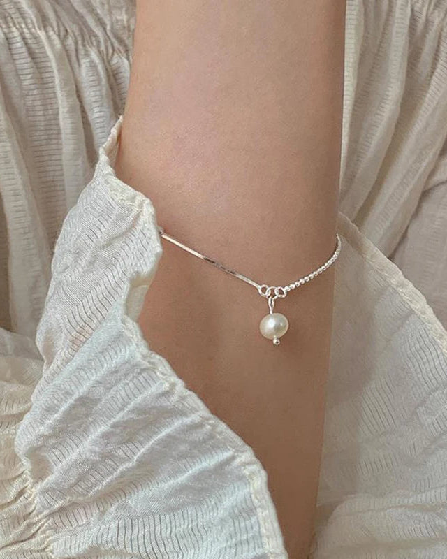 Elegant women’s silver bracelet with pearl pendant – styled on wrist with ruffle sleeve