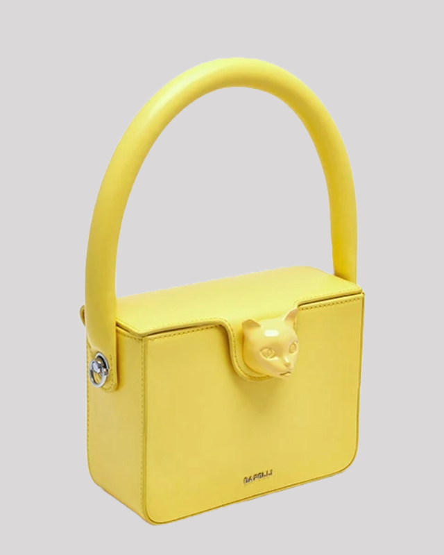 Side angled view of yellow Bafelli cat-handle bag with rounded handle and cat clasp