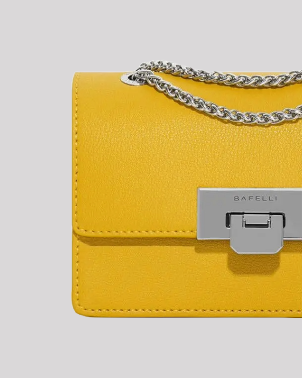 Close-up of yellow mini crossbody bag by Bafelli showing textured leather and metallic clasp closure