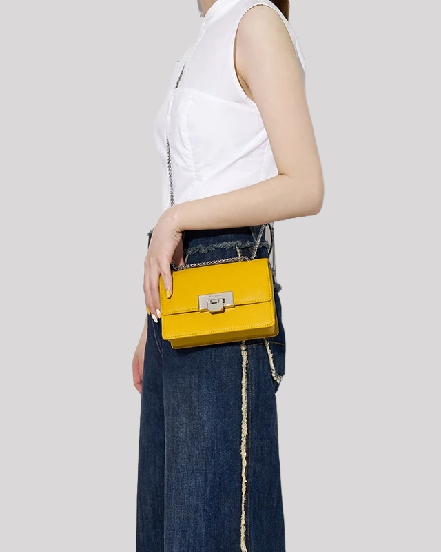Yellow mini crossbody bag by Bafelli worn crossbody with silver chain strap and metallic clasp