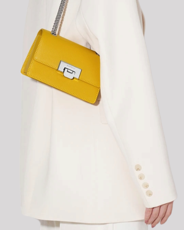 Side view of yellow mini crossbody bag by Bafelli worn crossbody with chain strap and clasp detail